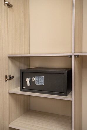 Una caja fuerte negra con teclado y cerradura, montada sobre un estante de madera en una habitación con paredes y puertas de madera.