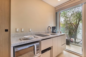 A modern kitchen with a granite countertop, stainless steel appliances, and a large window offering a view of the street. - TO BE SUITES (Ciudad de México)