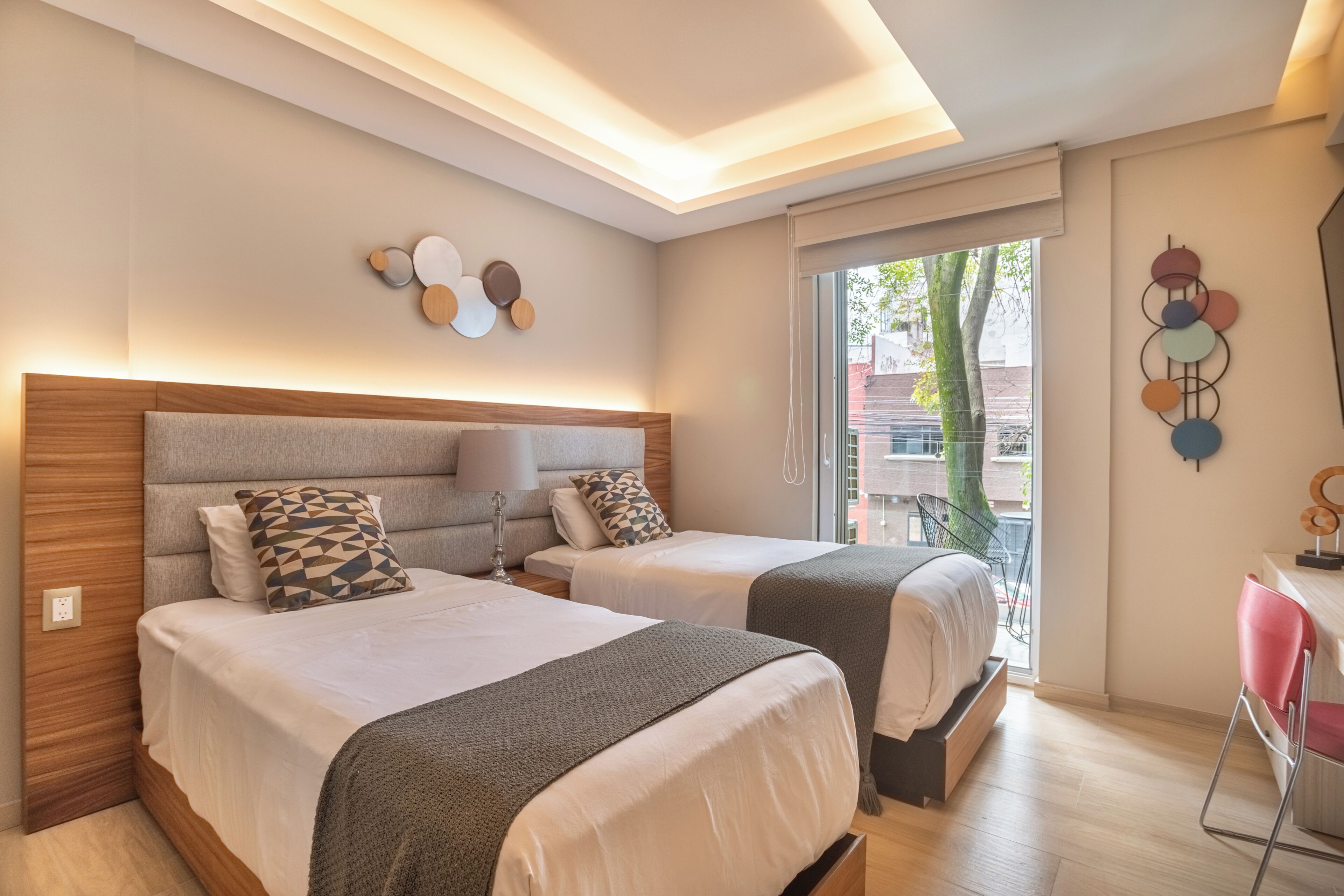 Ett modernt hotellrum med två sängar, ett skrivbord och utsikt över omgivningarna.