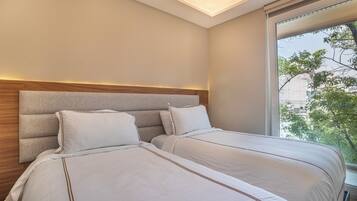Een hotelkamer met een groot raam, een houten hoofdbord en twee bedden met witte lakens.