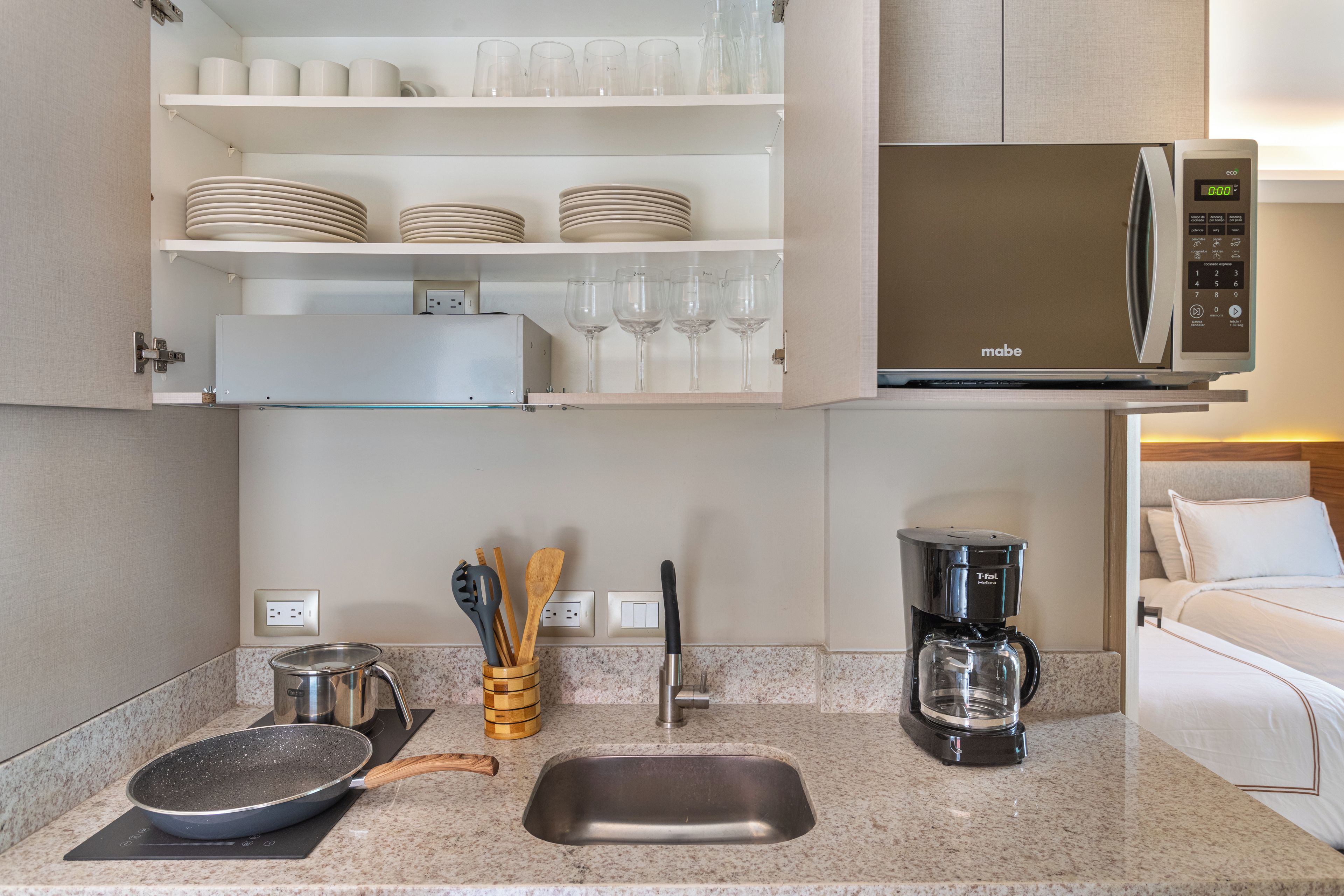 A modern kitchen with a microwave, coffee maker, and a sink.
