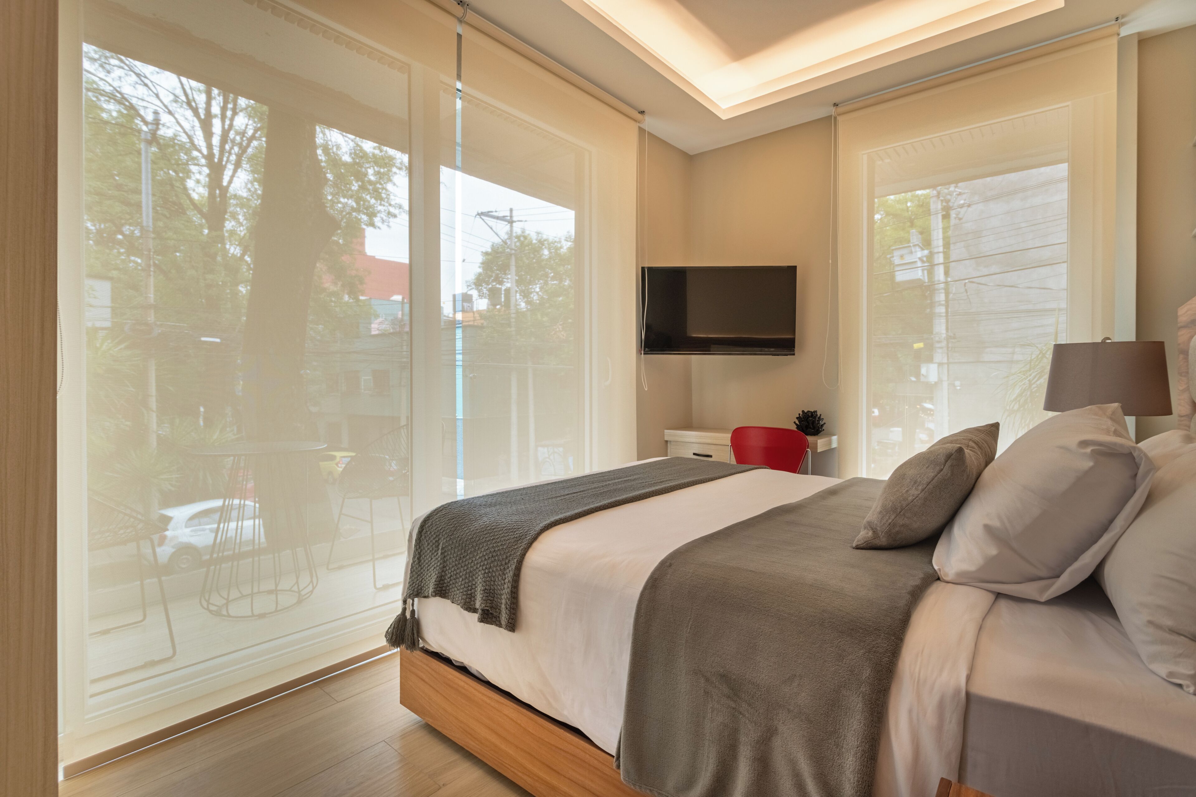 Une chambre à coucher avec un lit, une télévision, une fenêtre et une vue sur l’extérieur.