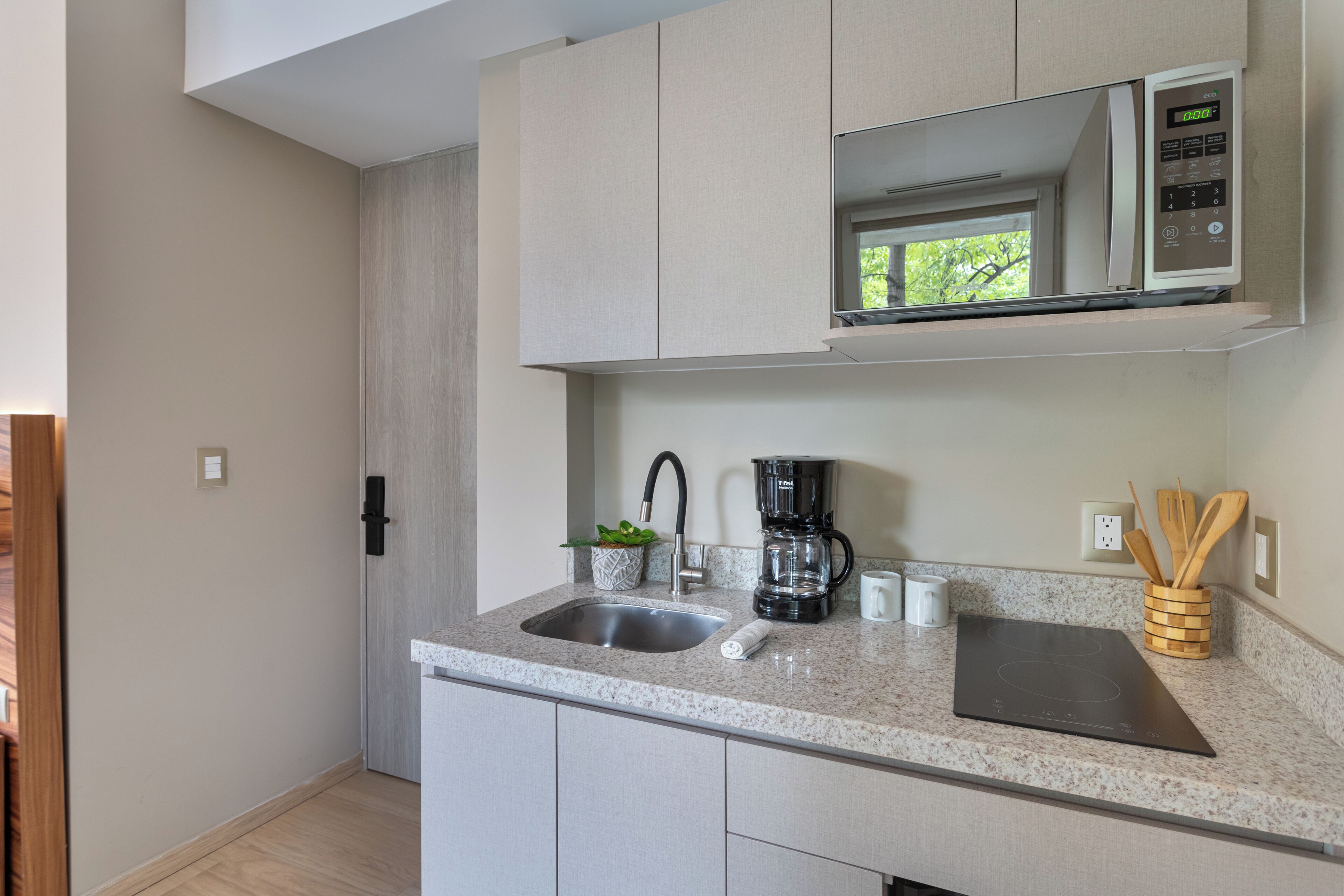 A modern kitchen with a built-in microwave, a coffee maker, and a sink.