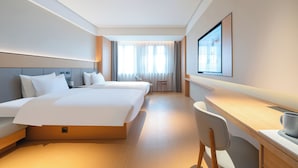 A hotel room with a large bed, a desk, and a chair.