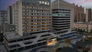 A modern hotel with multiple floors, a prominent entrance, and a well-lit facade.