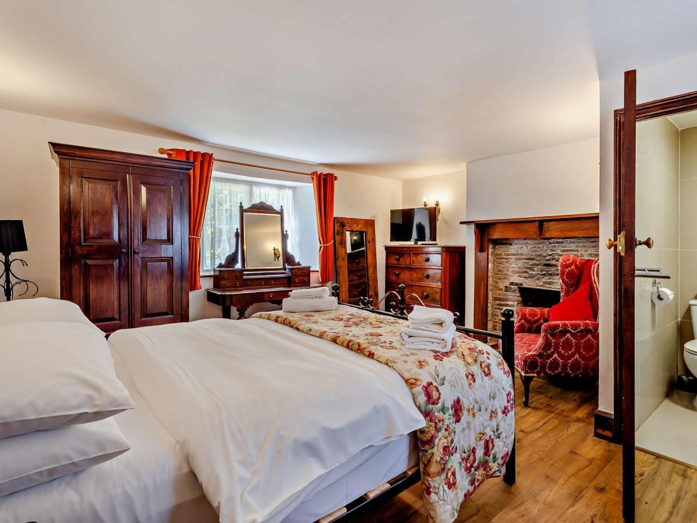 Ein Schlafzimmer mit einem großen Bett, einem Holzschrank, einer Kommode und einem roten Sessel.