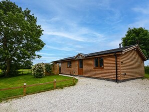 Une cabane en bois avec une allée en gravier et une clôture en bois.