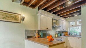 Een keuken met witte kastjes, een houten aanrechtblad en een hanglamp.