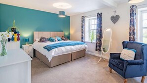 Une chambre à coucher avec un lit, une table de chevet, une chaise et un miroir.
