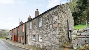 Un bâtiment en pierre avec une porte rouge, une fenêtre et un mur en pierre.