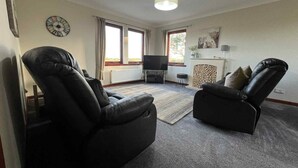 A living room with two leather recliners, a television, a fireplace, and a clock on the wall. - 3 Bed in Newton Stewart (oc-87541) (Mochrum)