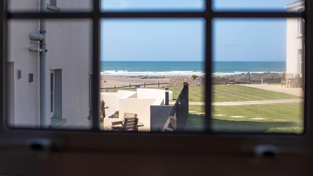 Une vue à travers une fenêtre, avec un océan bleu et une plage en arrière-plan.