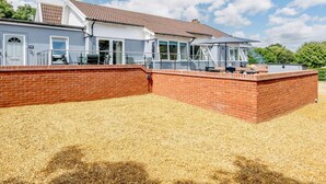 Ein zweistöckiges Haus mit Ziegelaußenwand, großen Fenstern und einer überdachten Terrasse.