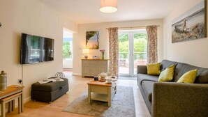Ein Wohnzimmer mit Sofa, Fernseher, Couchtisch, Schrank und einem Gemälde an der Wand.