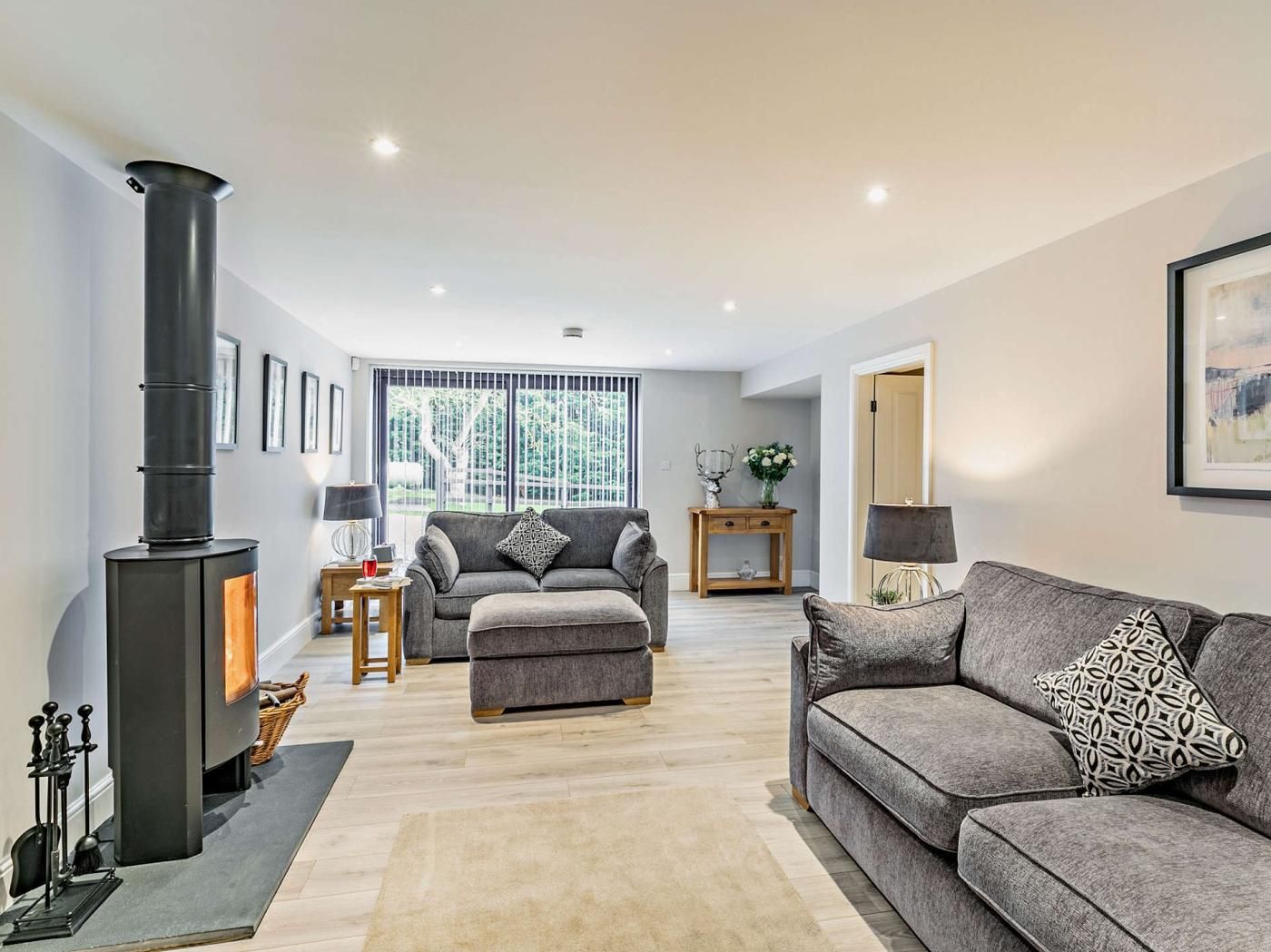 A modern living room with a fireplace, grey sofas, and a large window.