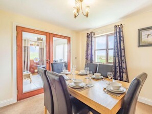 A dining room with a wooden table set for four, two chairs on each side, a chandelier, and a view through the window. - 3 Bed in Berwick-upon-tweed (oc-87777) (Lamberton)