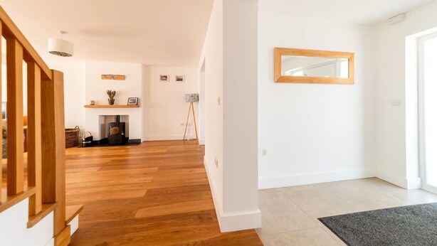 Uma sala de estar ampla, com piso de madeira, lareira e um cavalete.