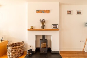 Ein modernes Wohnzimmer mit Kamin, einem Holzbodenregal mit Dekoration und einem gewebten Korb.