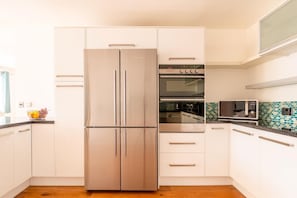A modern kitchen with a stainless steel refrigerator, built-in oven, and microwave. - 3 Bed in Bude (oc-87256) (Bude)