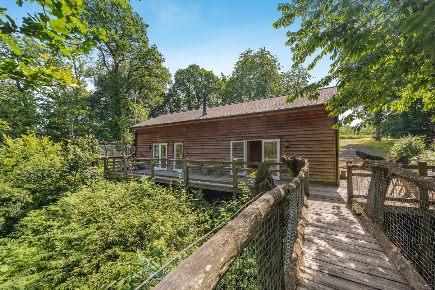 Eine Holzhütte mit Terrasse, umgeben von dichtem Grün.