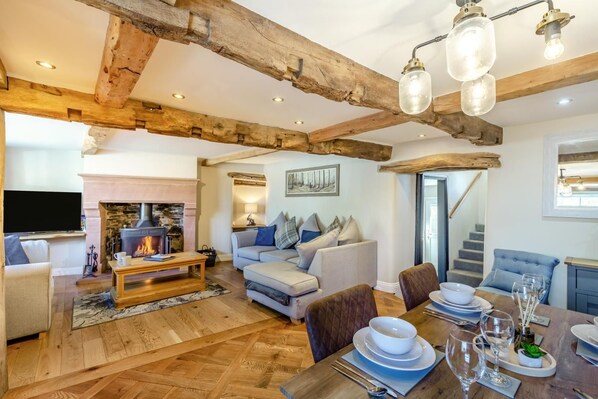 A cozy living room with a fireplace, a dining area set for a meal, and a staircase leading to another level.