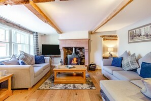 A cozy living room with a fireplace, sofas, a coffee table, and a television.