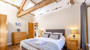 Un dormitorio con cama, armario de madera, mesitas de noche y un tragaluz.