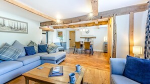 Una sala moderna con un sofá seccional, una mesa de centro de madera y un comedor con mesa y sillas.