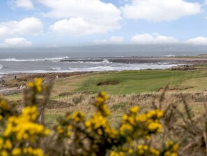 A coastal golf course with a view of the ocean and distant mountains. - 2 Bed in Porthcawl (oc-87294) (Porthcawl)