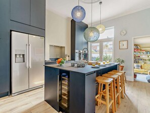 A modern kitchen with a built-in island, bar stools, a water dispenser, and a view of the outside.