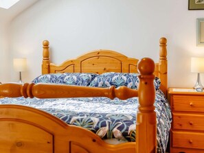 A wooden four-poster bed with a floral bedspread, a nightstand with a lamp, and a wall-mounted picture frame. - 2 Bed in Appleby-in-westmorland (oc-87537) (Long Marton)