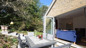 An outdoor patio with a table and chairs, a blue sofa, and a glass door leading to an interior space. - 4 Bed in Bakewell (oc-87419) (Bakewell)
