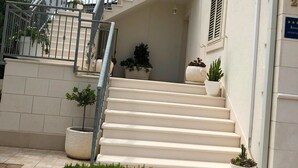 A staircase leading to a building entrance, with potted plants and a small lawn area. - Deluxe Two Bedroom Apartment with Terrace (Supetar)