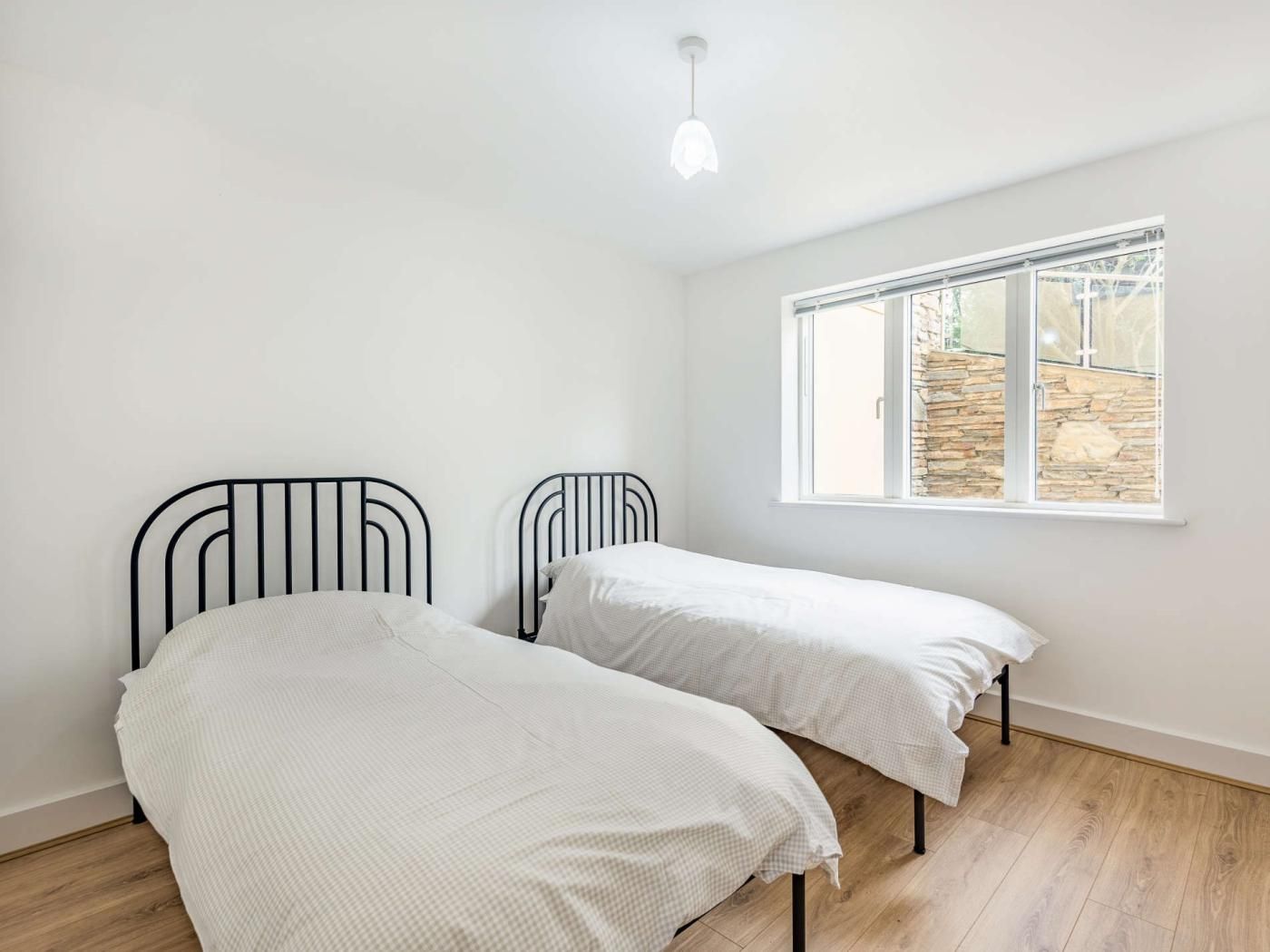 Ein Zimmer mit zwei Betten, einem Fenster und einer Hängeleuchte.