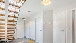 En modern inredning med en trappa, vita dörrar och en matta med geometriskt mönster.
