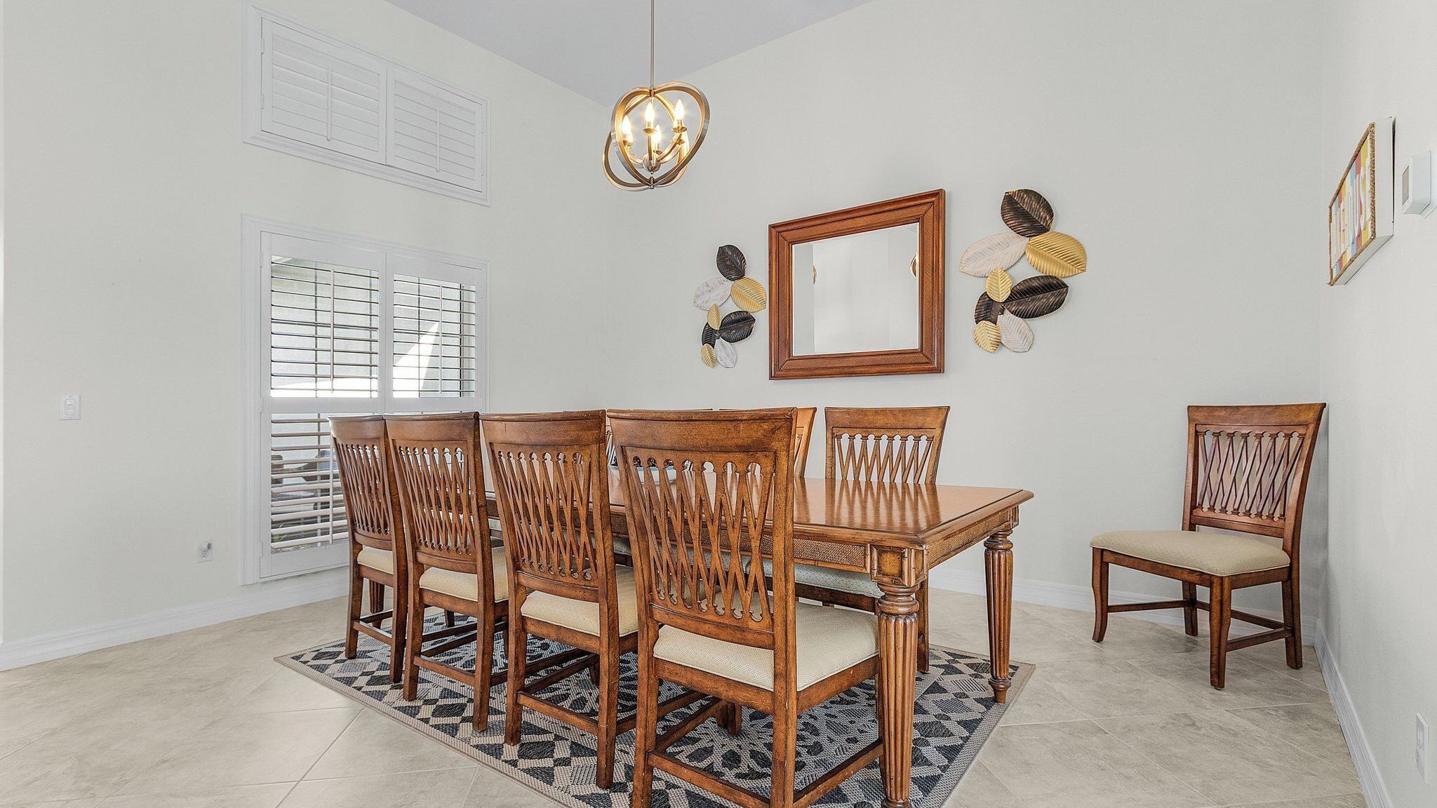 A dining area with a wooden table and chairs, a chandelier, and decorative wall art.