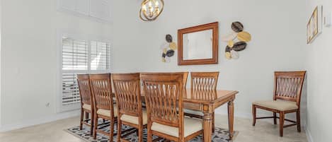 A dining area with a wooden table and chairs, a chandelier, and decorative wall art.
