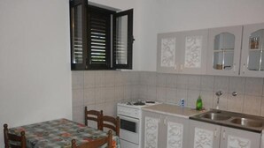 Une cuisine de taille réduite comprenant une table à manger, des chaises, une cuisinière et des placards.