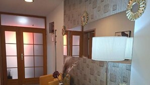 A room with a wooden door, a standing lamp, and patterned wallpaper.