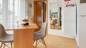 A compact living space with a dining area, kitchenette, and a mirror reflecting the room.