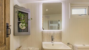 Une salle de bain avec un lavabo, un miroir et un meuble en bois.
