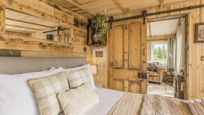 Une pièce rustique en bois, avec un lit, un canapé et une porte donnant sur une autre pièce.