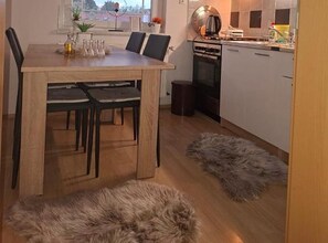A dining area with a wooden table, black chairs, a small rug, and a view of the outdoors through a window. - Classic One Bedroom Apartment with Terrace (Vukovar)