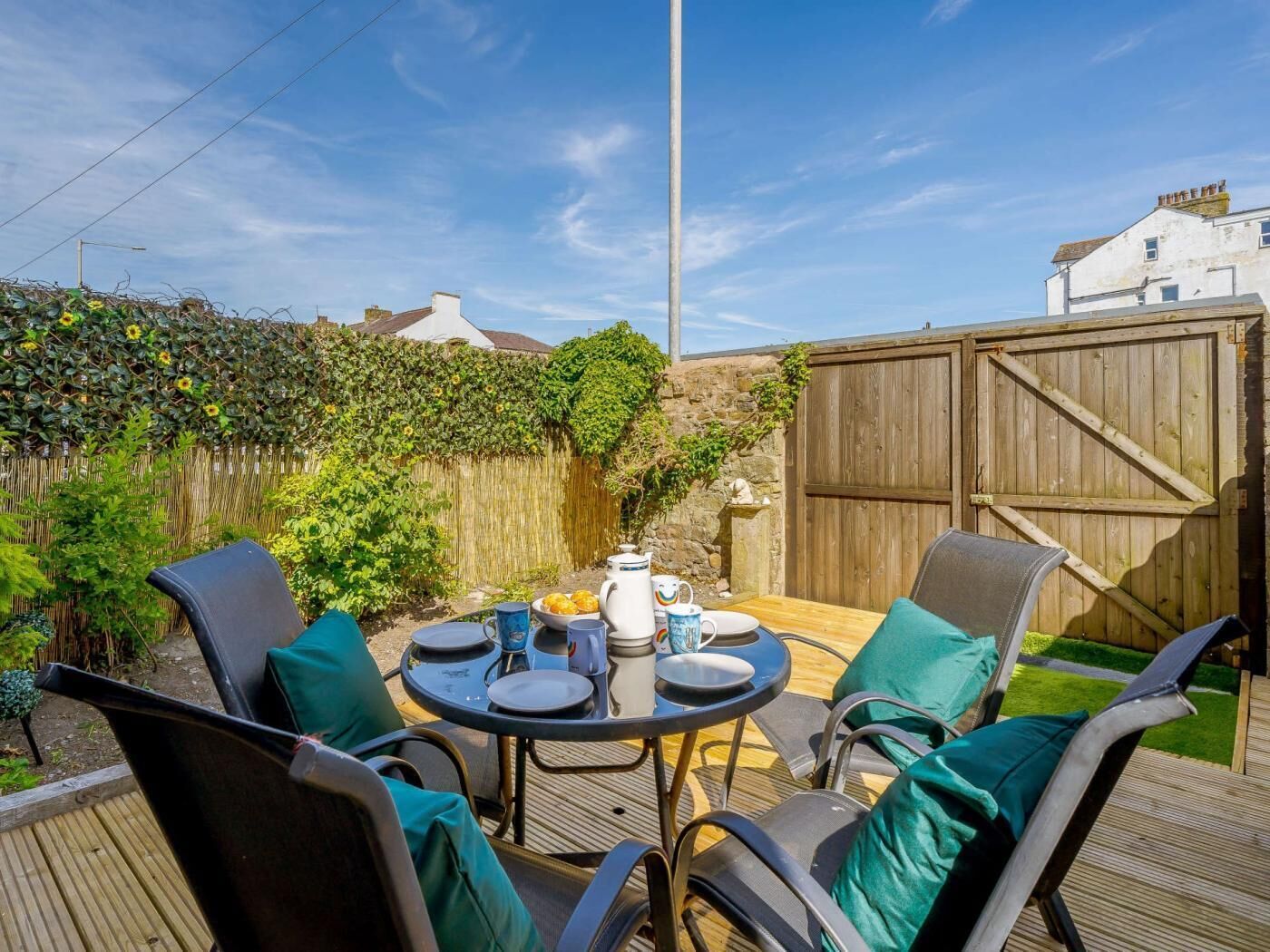 A patio with a round table, four chairs, and a wooden fence in the background.