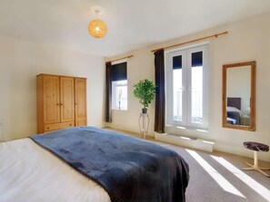 A bedroom with a bed, a wardrobe, a window with curtains, a potted plant, and a mirror. - 5 Bed in Morecambe (oc-87639) (Heysham)