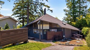 Ein modernes Haus mit Satteldach, großen Fenstern und einer Holzterrasse.