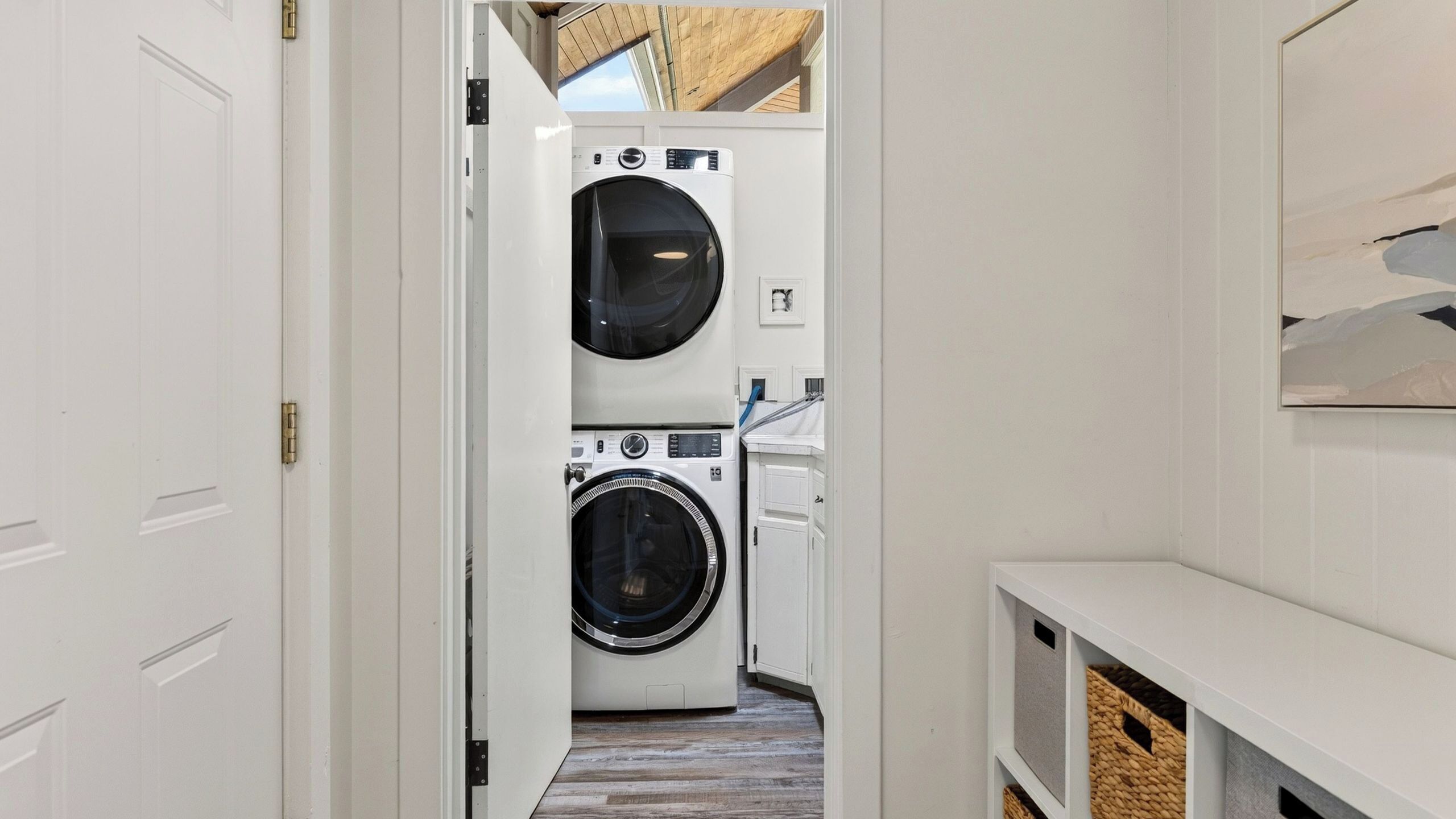 A laundry room with two washing machines, a sink, and a wooden ceiling.