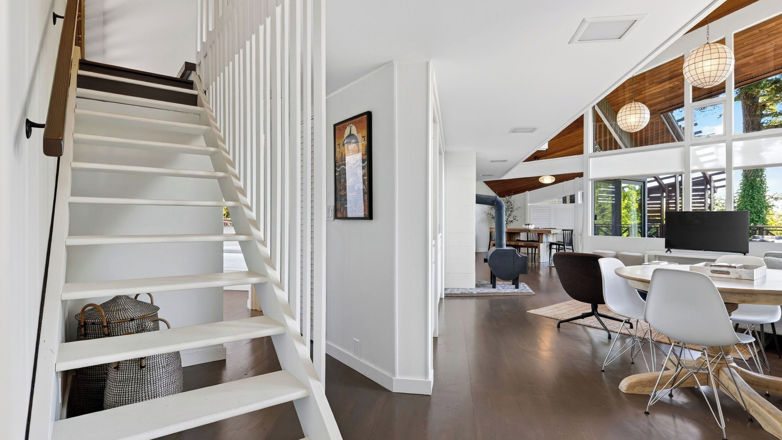 A modern interior with a staircase, a dining area, and a TV.