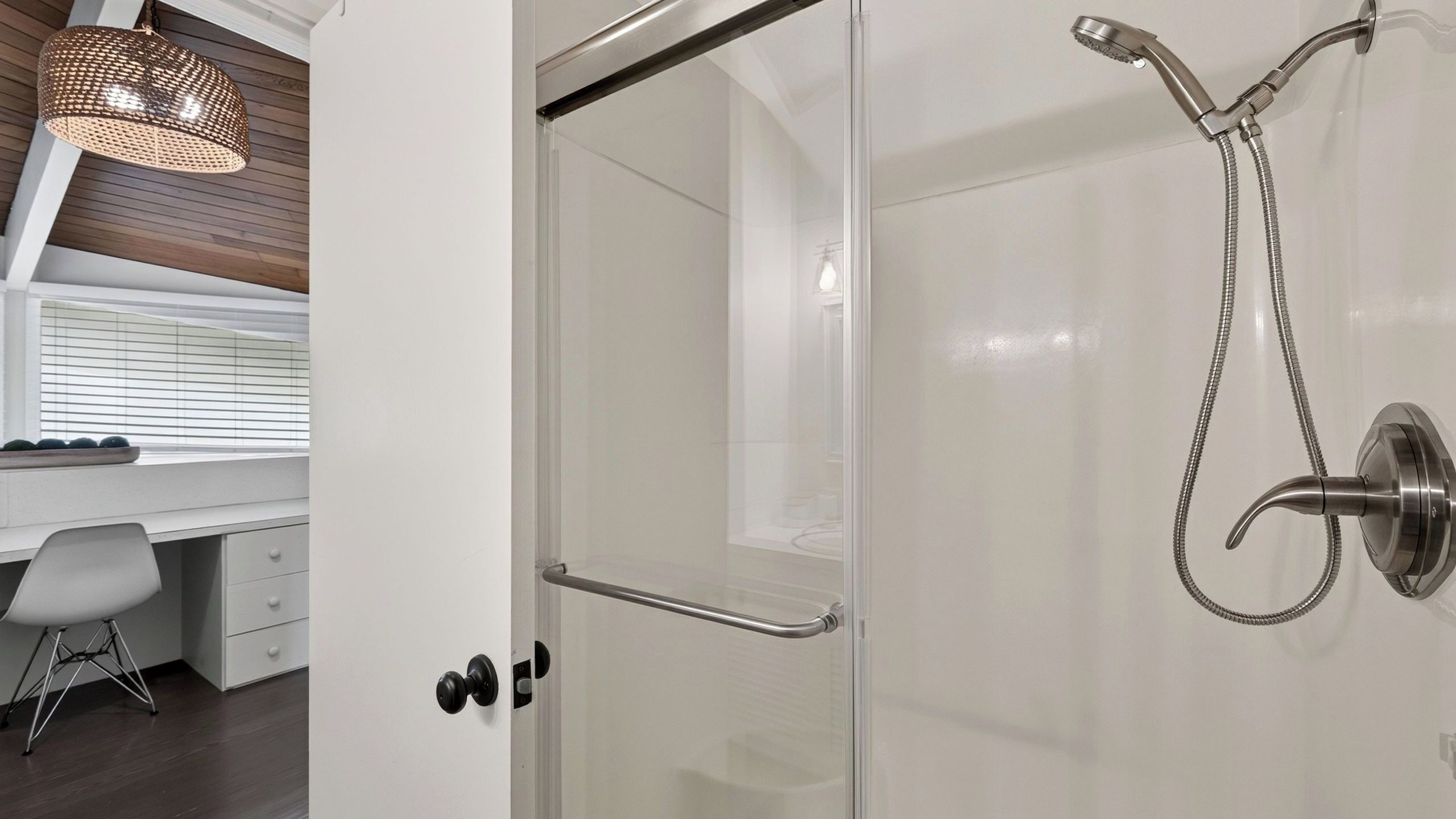 A modern bathroom with a glass shower enclosure, a towel rack, and a pendant light.