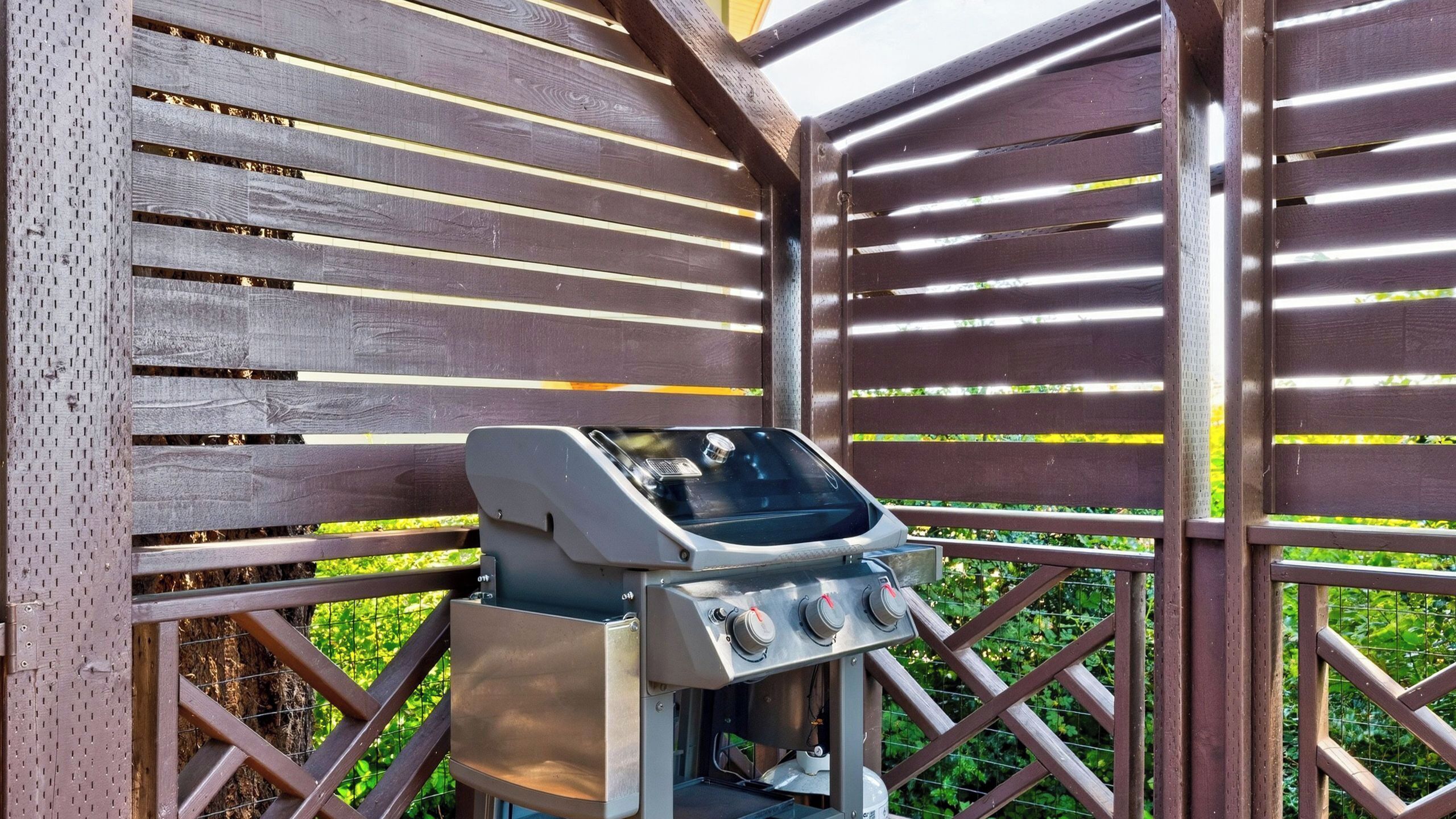 A barbecue grill with a digital display, set against a wooden fence with a lattice design.